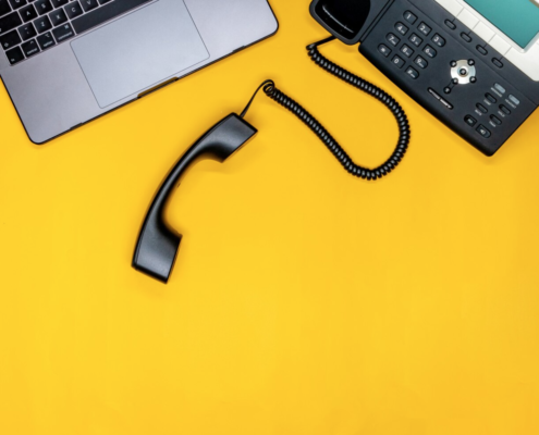 A yellow desk top looking down at a laptop and VOIP phone