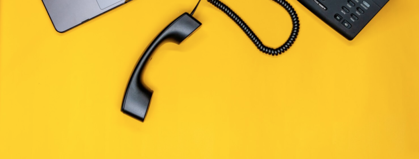 A yellow desk top looking down at a laptop and VOIP phone